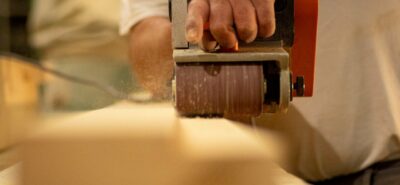 Man using a sanding belt with a push sander